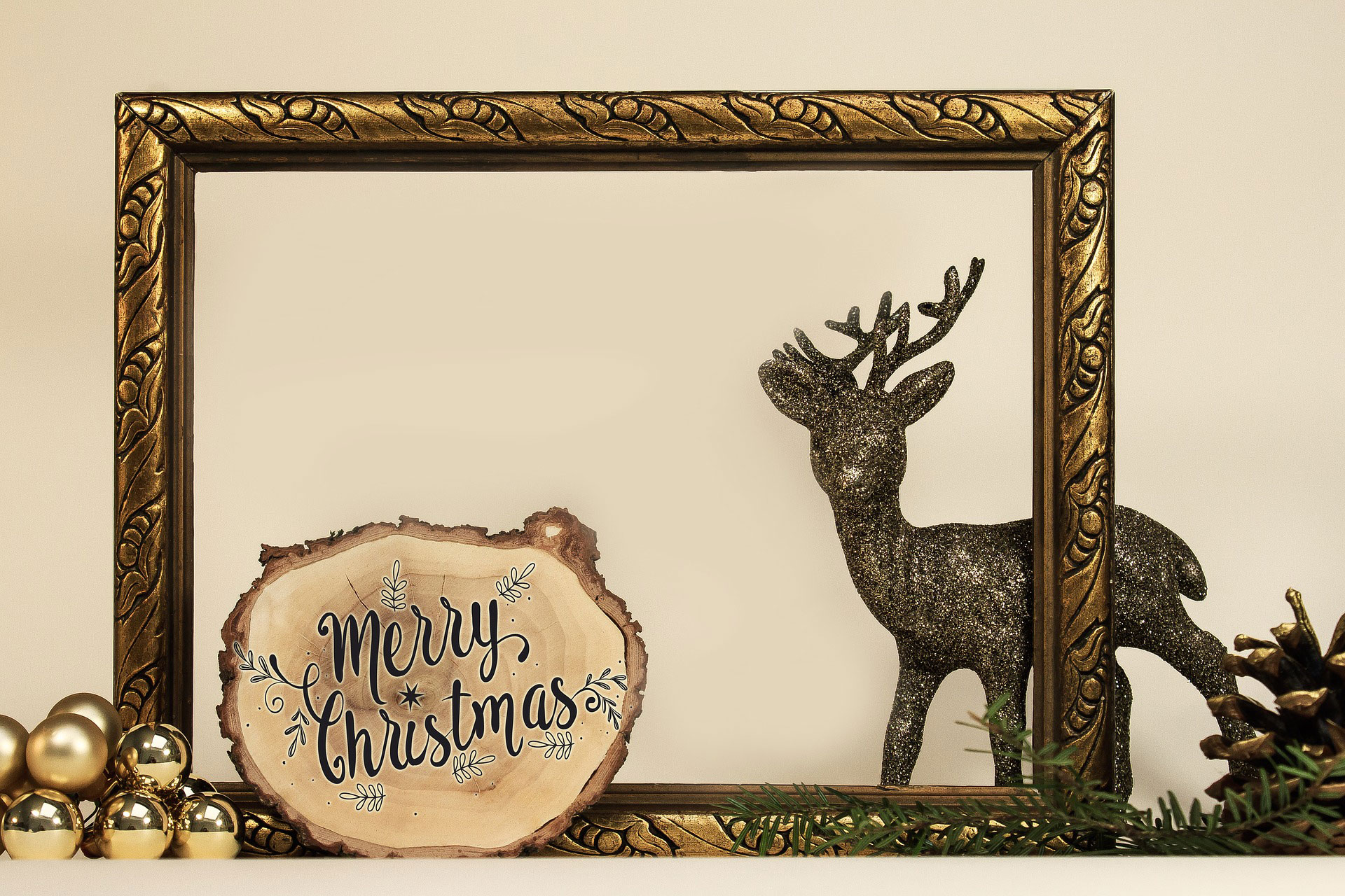 Holzscheibe mit der Aufschrift Merry Christmas vor einem goldenen Holzrahmen und einem Deko-Hirsch